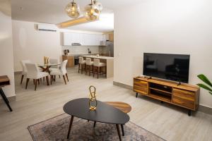 Cumbres Garden luxury apartments في كانكون: غرفة معيشة مع تلفزيون وطاولة