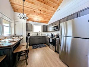 a kitchen with a stainless steel refrigerator and wooden ceilings at Acadia Sunset Fishing Cabin #2 family beach fire pit in Sullivan