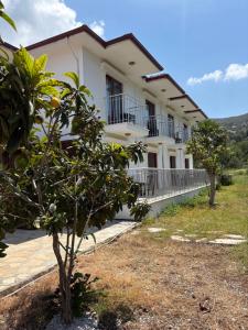 a white building with trees in front of it at Ebru'ca Pansiyon in Selimiye