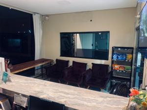 a room with a bar with chairs and a television at Hotel Arara Azul in Pontes e Lacerda