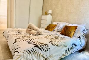 a bedroom with a bed with a white comforter with leaves at Temple Luxe- Balnéo et Jardin, wifi, parking privé securisé in Béziers