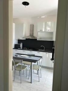 Torre InserraglioにあるVilla Rubinoの白いキャビネットとテーブルと椅子のあるキッチン