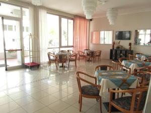 a dining room with tables and chairs and windows at Hotel Admiral in Cesenatico