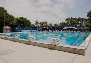 a large swimming pool with blue water at Tiny Comfy flat with Bikes in Coolum Beach