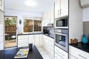 a white kitchen with white cabinets and appliances at Tiny Comfy flat with Bikes in Coolum Beach +22 photos