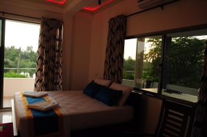 a bedroom with a bed and a large window at Kamaro Holiday Resorts (Villa) in Bandaragama
