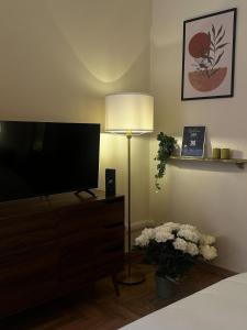 uma sala de estar com uma televisão, um abajur e flores em The Apartment 56 em Roma mais 14 fotografias