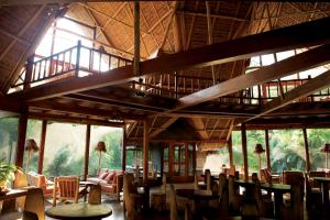 un restaurante con mesas y sillas de madera y ventanas en Inkaterra Reserva Amazonica, en Puerto Maldonado