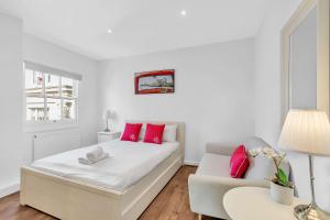 a white bedroom with a bed and a couch at Slice of Brighton With Seaviews By My Getaways in Brighton & Hove