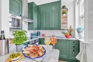 a green kitchen with a plate of food and wine glasses at Slice of Brighton With Seaviews By My Getaways in Brighton & Hove