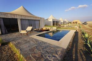 a backyard with a swimming pool and a house at The White Camel Camp - Agafay Desert Activities in Marrakesh
