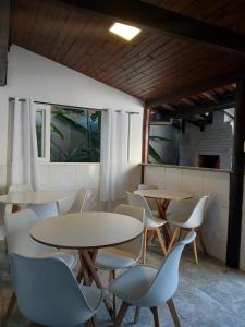 two tables and chairs in a room with windows at Pousada Recanto da Luísa in Paraty