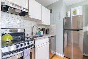 a kitchen with white cabinets and a stainless steel refrigerator at Eclectic Downtown & Cap Hill King bed & Kitchen in Seattle