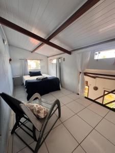 a bedroom with a bed and a chair in a room at Casa de Mainha Arraial in Arraial d'Ajuda