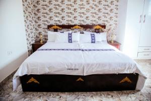 een slaapkamer met een groot bed met witte lakens bij CK Suites in Adentan +21 foto's