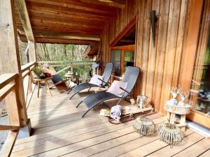 a porch with rocking chairs on a wooden house at La Linotte in Arville