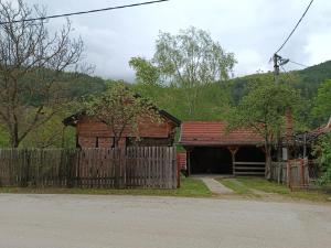 a wooden barn with a fence next to a house at Seosko turisticko Domaćinstvo Radivojević in Kraljevo