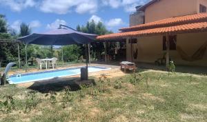 una piscina con ombrellone accanto a una casa di Casa Nativa Coqueiro a Luis Correia