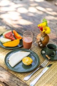 a table with two plates of food and a glass of juice at Vila Botanika Caraíva in Caraíva