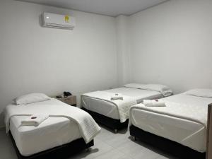 three beds in a room with white walls at OMA HOTEL LA GUAJIRA in Camarones