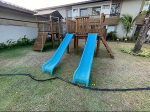 a playground with a blue slide in a yard at Village itacimirim completo in Camacari