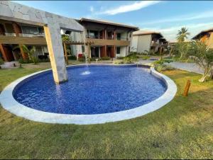 a large blue pool in front of a house at Village itacimirim completo in Camacari