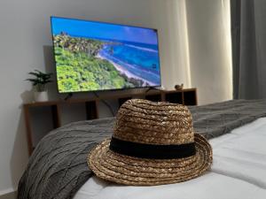 un chapeau de paille posé sur un lit avec une télévision dans l'établissement Beach Haus-Punta Estrella, à Playa del Carmen