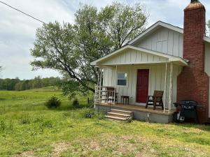 a small white house with a red door on a field at Mountain View Cottage in Ashland