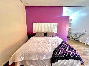 a bedroom with a large bed with a purple wall at Villa - Dar Tura in Tikoutar