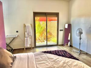 a bedroom with a bed and a large window at Villa - Dar Tura in Tikoutar