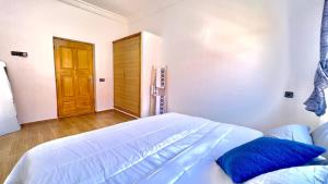 a bedroom with a white bed with a wooden door at Villa - Dar Tura in Tikoutar