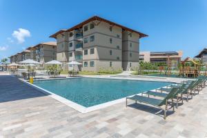 ein Swimmingpool mit Stühlen und einem Gebäude in der Unterkunft Itah Residence Muro Alto Beira Mar in Ipojuca