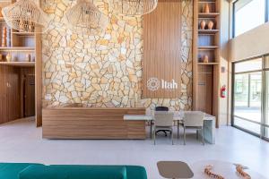 eine Lobby mit einem Tisch, Stühlen und einer Steinmauer in der Unterkunft Itah Residence Muro Alto Beira Mar in Ipojuca