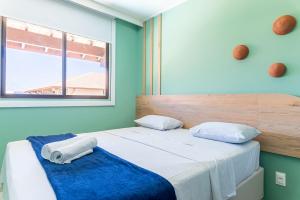 1 Schlafzimmer mit 2 Betten mit blauen Wänden und einem Fenster in der Unterkunft Itah Residence Muro Alto Beira Mar in Ipojuca + 52 Fotos