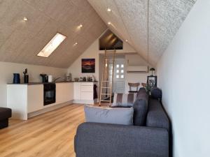 a living room with a couch and a kitchen at Eiðsvíkslon - The Red Boathouse by the Sea in Viðareiði
