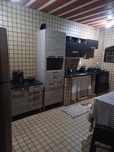 a kitchen with stainless steel appliances and a tiled wall at Cantinho do Aconchego in Iguaba Grande