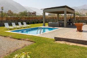 a swimming pool with a gazebo and chairs at Ecohouse Cieneguilla in Pachacamac