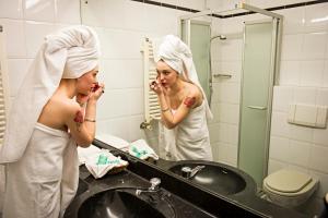 a woman brushing her teeth in a bathroom mirror at Hotel Cinzia Ristorante Christian e Manuel in Vercelli +48 photos