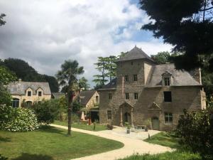 a large stone house with a palm tree in the yard at Métairie du Manoir Comfortable holiday residence in Le Vieux-Marché