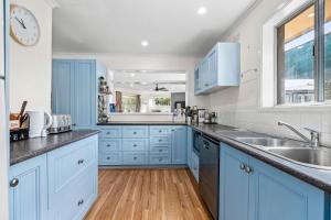 een keuken met blauwe kasten en een wastafel bij The Abbey in Point Lonsdale