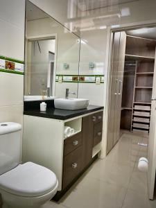 a bathroom with a toilet and a sink and a mirror at Casa 2 Suítes+1 - VISTA MAR e 15km do Beto Carrero - 50 metros da PRAIA - Area de LAZER com Churrasqueira - Wi-Fi e Cozinha Completa in Piçarras