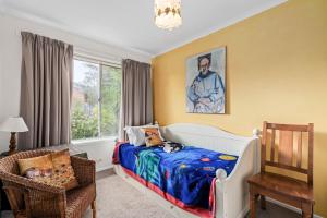 een slaapkamer met een bed, een stoel en een raam bij The Abbey in Point Lonsdale