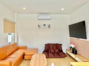 a living room with a couch and a flat screen tv at บ้านหมอบิวพูลวิลล่า Baanmhorbewpoolvilla in Chiang Khan