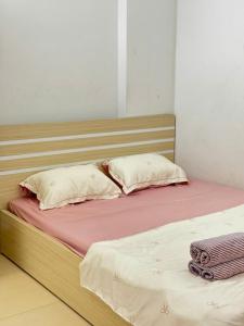 a bed with a wooden headboard and two pillows at Someli in Hanoi