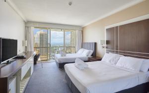 ein Hotelzimmer mit zwei Betten und einem Fernseher in der Unterkunft Private Hotel Rooms in Central Surfers in Gold Coast