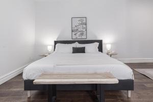 a bedroom with a large white bed with a bench on it at Ann Avenue Modern 3BR Home, Near Downtown with Free Parking in Saint Louis