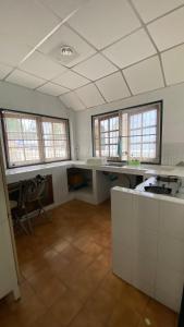 an empty room with a kitchen with a counter and windows at Kiang Beach Villa Cha-am in Cha Am