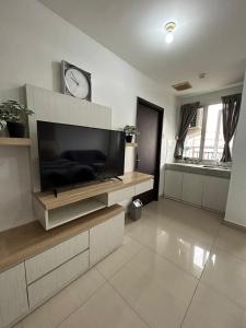 a living room with a tv and a clock on the wall at 1BR Plus Sudirman Suite Apart by Metta in Bandung