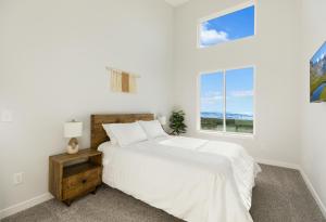 a white bedroom with a bed and two windows at The Beachcomber - Oceanfront Getaway! in Westport