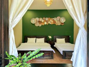 two beds in a room with a green wall at Du Yen Garden Mang Đen in Kon Von Kla